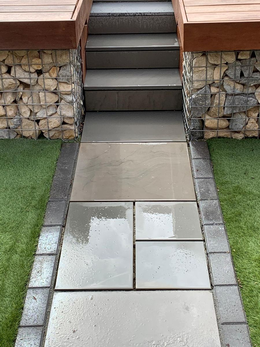 Paved path leading to steps between stone gabion walls